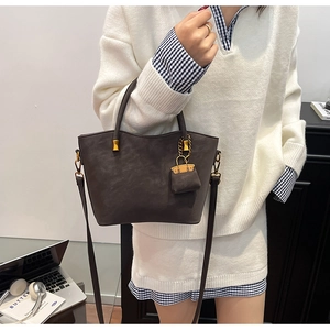 Detail of vintage brown tote bag with mini bag charm and gold hardware accents