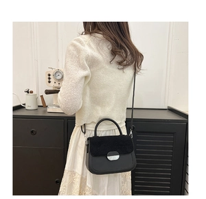 Detail of elegant black saddle bag with silver buckle worn by a model in a lifestyle scene