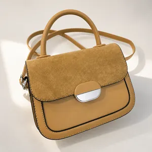Detail of camel saddle bag featuring suede and leather contrast stitching with silver buckle
