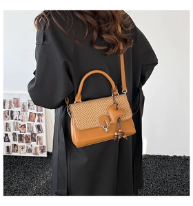 Bolso bandolera marrón con textura tejida sobre un abrigo de lana negro