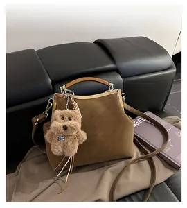Détails d'un sac à main en daim marron avec anses en bois et breloque chiot