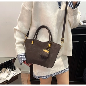 Detail of dark brown suede tote bag with golden hardware and mini pouch accessory