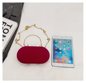 Size comparison of red velvet evening clutch bag with chain strap against an iPad mini