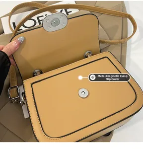 Close-up of the metal magnetic buckle and khaki leather flap on this shoulder bag