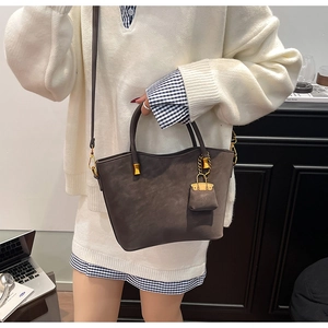Detail of dark brown faux suede tote bag with mini purse charm and gold hardware strap