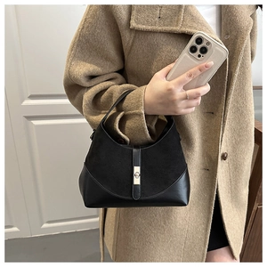 Dettaglio borsa a mano nera in pelle scamosciata con fibbia metallica su cappotto di lana beige