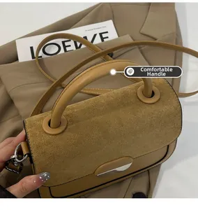 Detail of camel suede saddle bag showing comfortable handle and magnetic clasp closure
