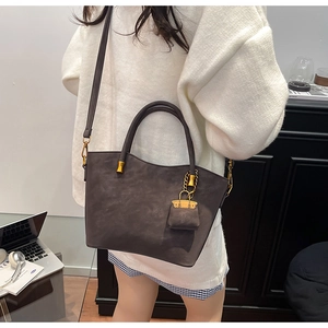 Detail of the wave-cut top and golden hardware on the dark brown tote bag