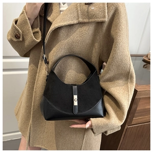Detail of black contrast texture handbag with metal turn-lock closure on model