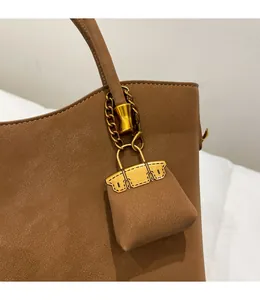 Detail of dark brown lychee leather tote featuring a detachable mini bag charm with gold chain
