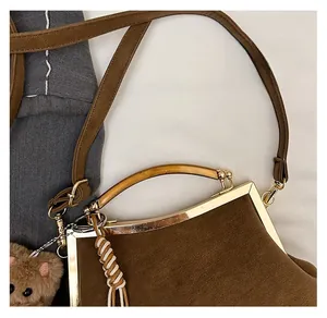 Gros plan du sac vintage marron avec poignée en métal doré et breloque ours en peluche