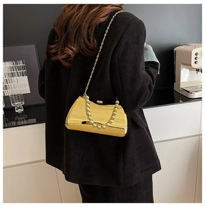 Detailed view of mirrored gold clutch with beaded handle and fine metal chain strap