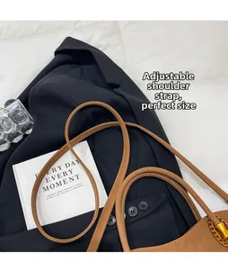 Brown leather handbag detail featuring adjustable shoulder strap and gold-tone chain accents
