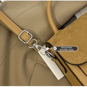 Detail of silver metal hardware and adjustable strap on a brown leather saddle bag