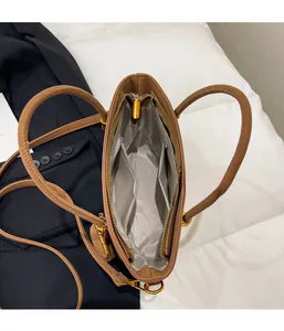 Interior view of brown tote bag showing zipper pocket and spacious gray lining