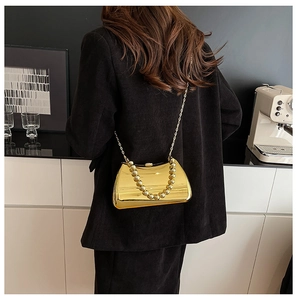 Golden metal box bag with acrylic chain handle worn over a black blazer for evening style