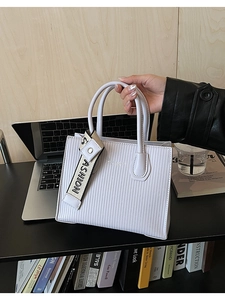 Close-up of light purple textured square handbag with a striped pattern and ASHION strap