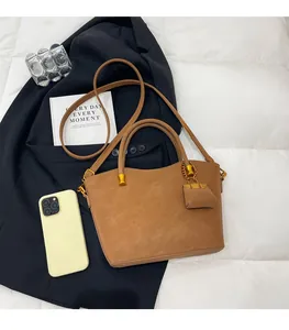 Detailed view of caramel brown leather tote bag with mini charm on a blazer background