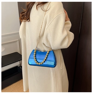 Detail of mirror blue evening clutch bag with golden bead handle and metal chain strap