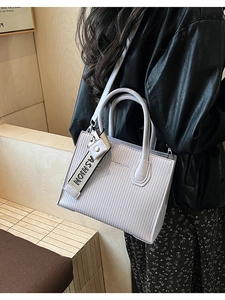 Detail of lavender textured tote bag with Fashion & Bags logo and striped leather surface