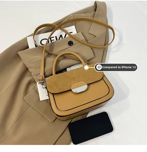 Brown saddle bag shown with iPhone 12 for size comparison on a blazer background