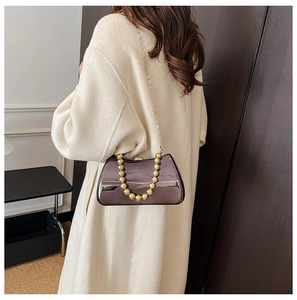 Detail of metallic evening box bag with gold bead handle and chain on wool coat