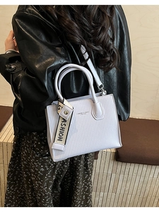 Crossbody view of light purple textured leather small square bag with fashion strap