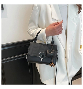 Detail of black crossbody bag featuring herringbone texture and heart charm