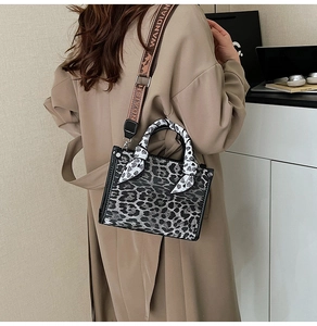 Detail of leopard print handbag featuring a floral silk scarf handle and wide canvas strap