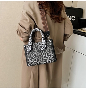 Detail of leopard print handbag with silk scarf wrapped handle and woven shoulder strap