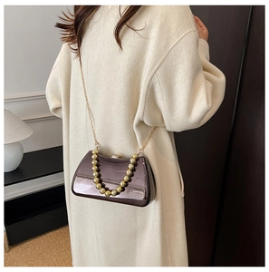 Detail of coffee-colored mirror evening bag with gold sphere handle and chain strap