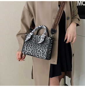Detail of leopard print handbag featuring a silk scarf handle and wide branded strap