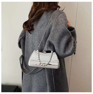 Detail of silver mirror evening clutch bag with round bead handle and metal chain strap