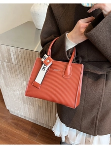 Close-up of caramel textured leather handbag with vertical pleats and decorative strap