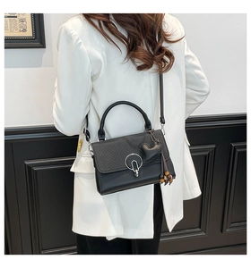 Detalle del bolso acolchado negro con herrajes plateados y colgante de corazón en blazer