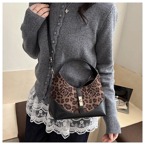 Detail of crossbody bag with floral leopard print, smooth black leather, and gold twist lock