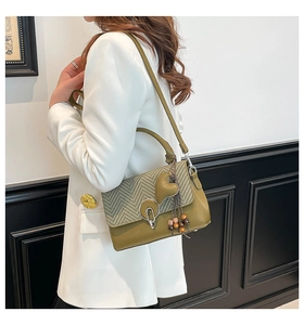 Detalle de bolso de cuero verde con estampado de pata de gallo y borla de madera