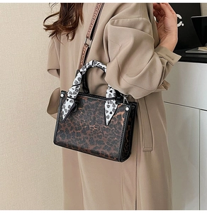 Detail of leopard print handbag with heart silk scarf handle and woven strap