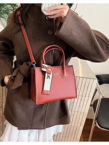 Detail of red-brown textured tote bag with Fashion & Bags lettering and woven strap