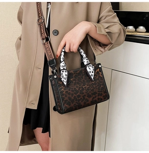 Detail of leopard print crossbody bag with silk scarf handle and wide branded strap