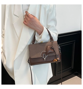 Detail of vintage brown tote with herringbone fabric flap and heart charm on white suit