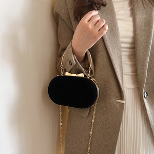 Elegant black velvet oval evening bag with gold bow clasp and metallic chain strap