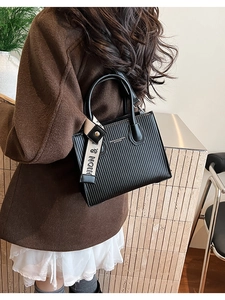 Detail of black pleated tote bag with fashion canvas strap and gold embossed lettering