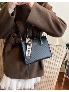Detail of black leather tote bag with vertical stripes texture and adjustable shoulder strap