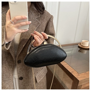 Detail of black oval clutch bag with gold ring handle and textured faux leather