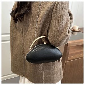 Detail of a matte black half-moon bag with golden metal handle and fine chain strap