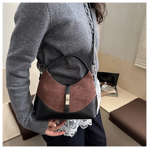 Detail of suede saddle bag with metal twist-lock and contrast stitching on the strap