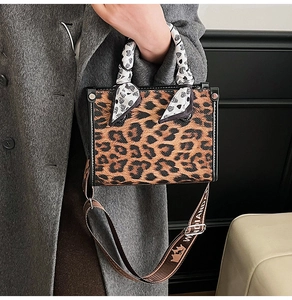 Close-up of leopard print handbag featuring a silk scarf handle and logo shoulder strap