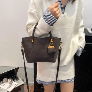 Classic dark brown matte leather tote bag with gold hardware and a mini bag charm
