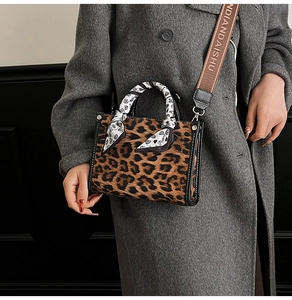 Detail of leopard print handbag with silk-wrapped handle and branded woven shoulder strap